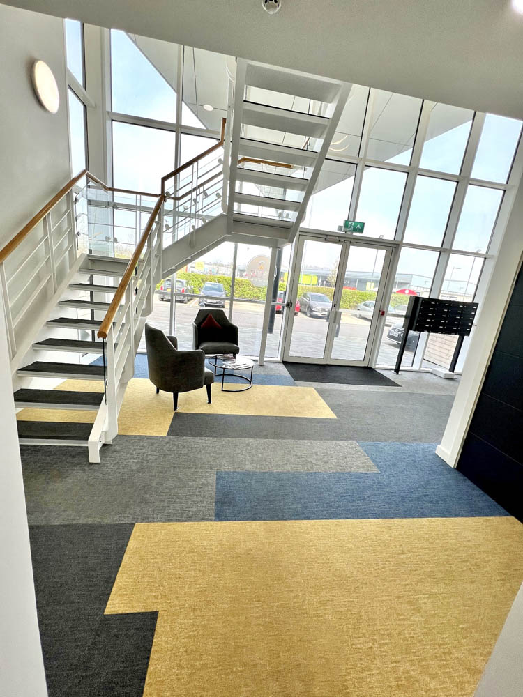 Main entrance to residential property with stairs and yellow carpet looking out to the car park