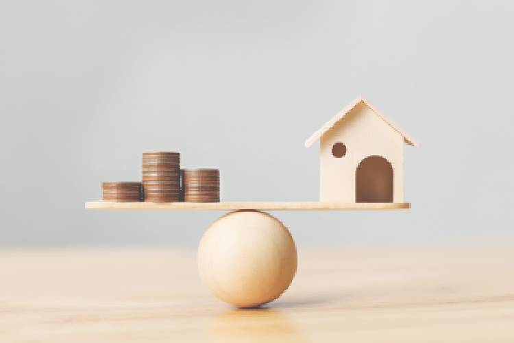 A wooden ball and scale with coins at one end and wooden house at the other