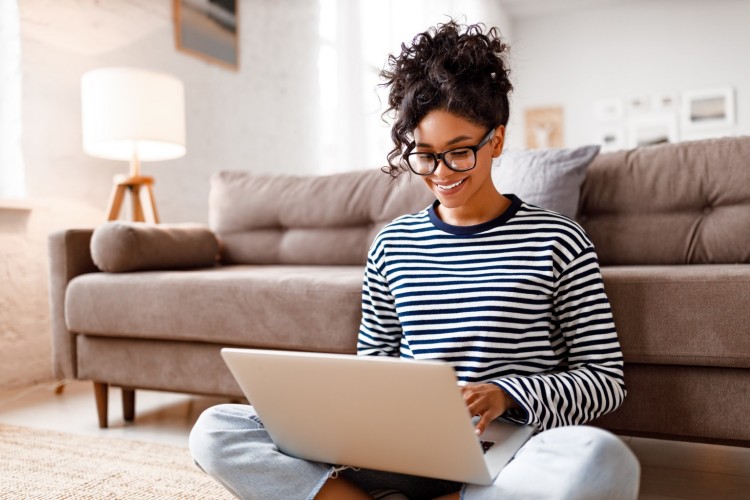 Woman sitting on the floor smiling with her laptop
