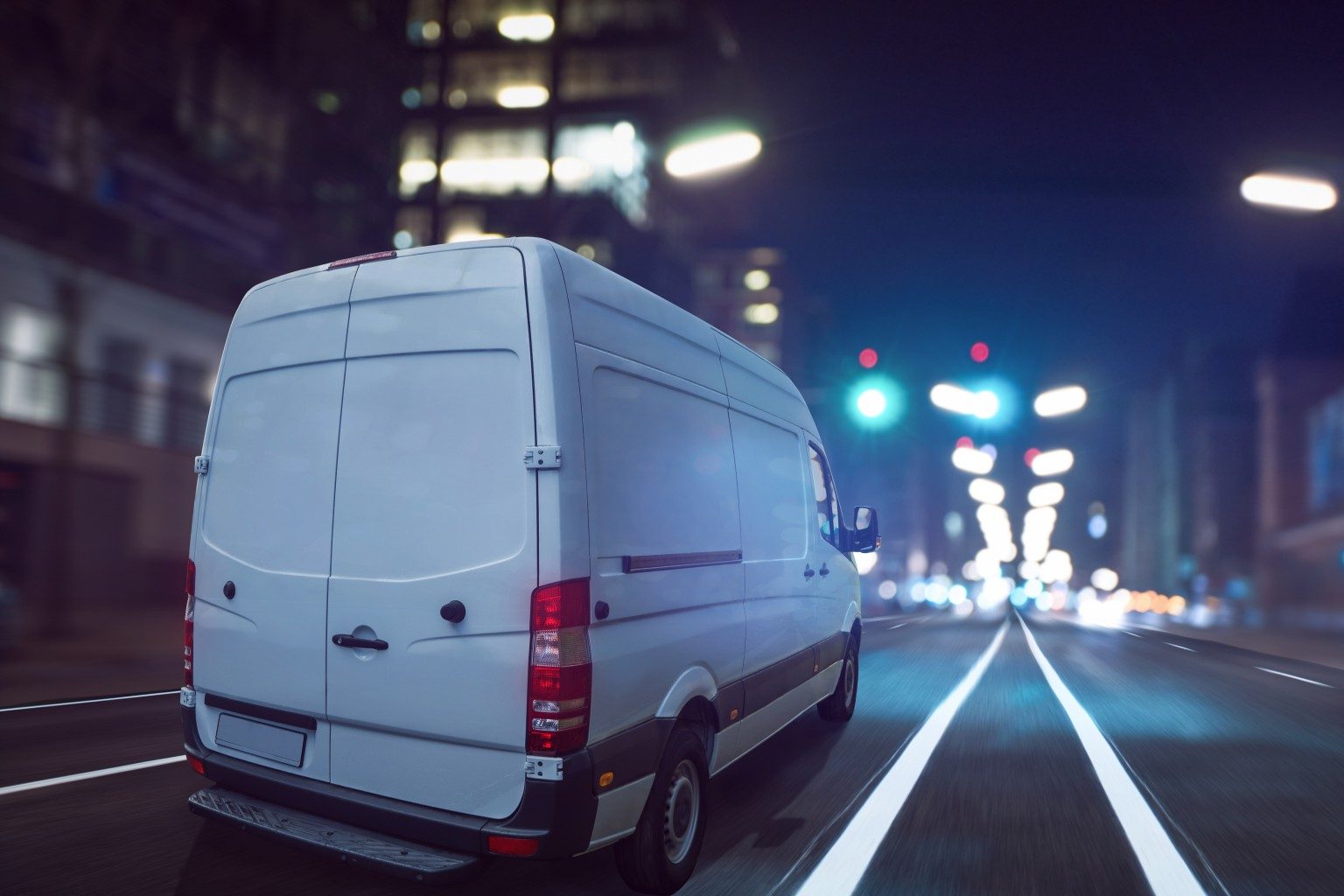 A white van on a city road at night