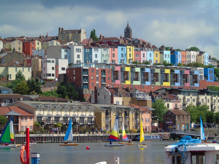 Rows of colourful buildings in Bristol on a hill with boats in the foreground