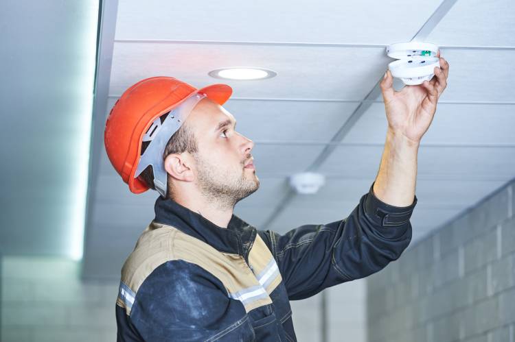 Man in a hard hat checking a fire alarm